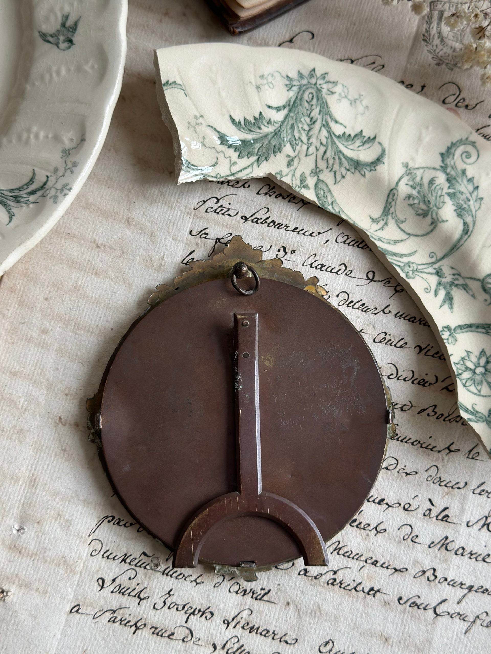 Cadre ancien rond bronze et motif terre de fer Gien Rinceaux