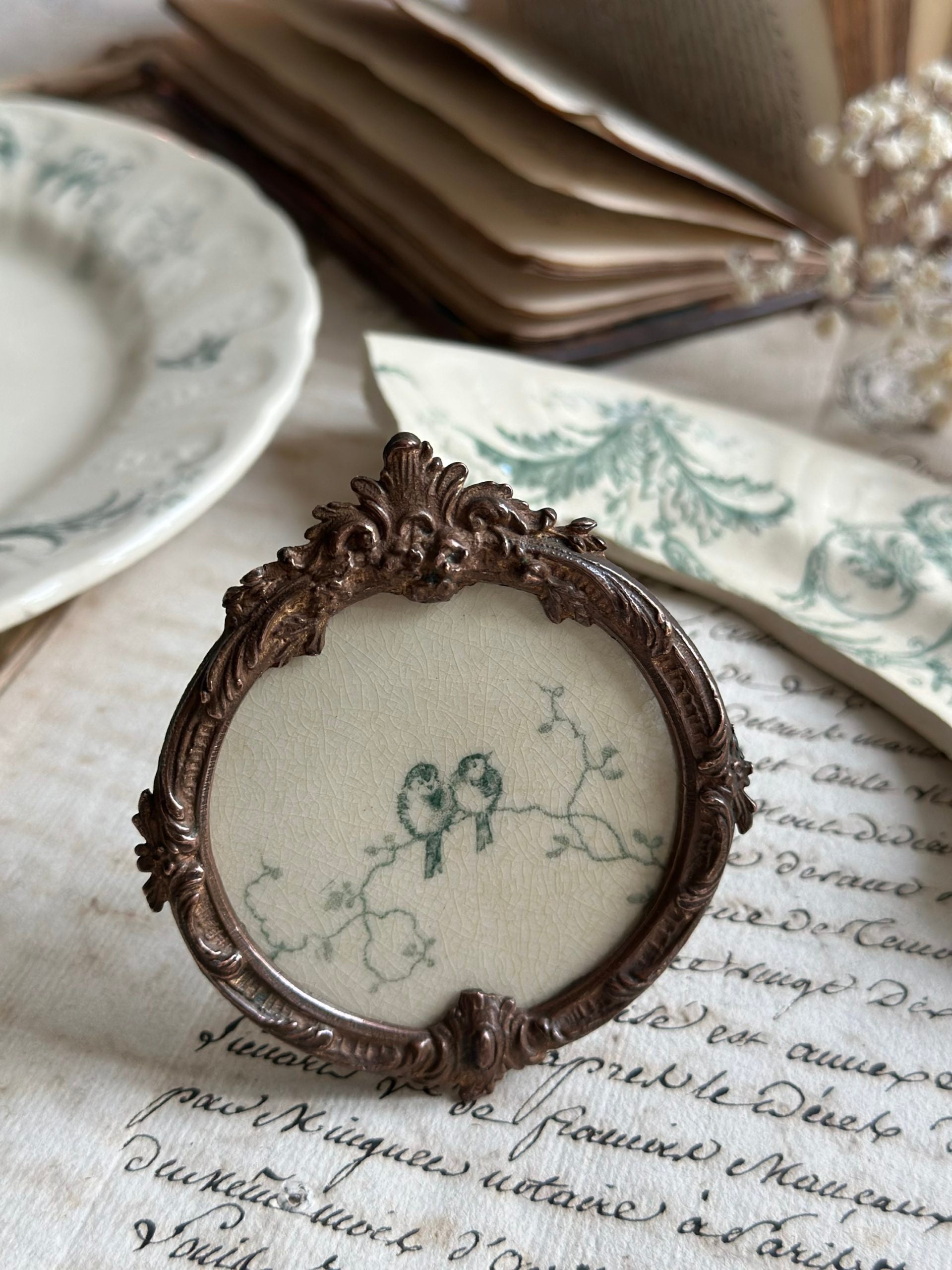 Petit cadre ancien rond bronze et motif terre de fer Gien Rinceaux