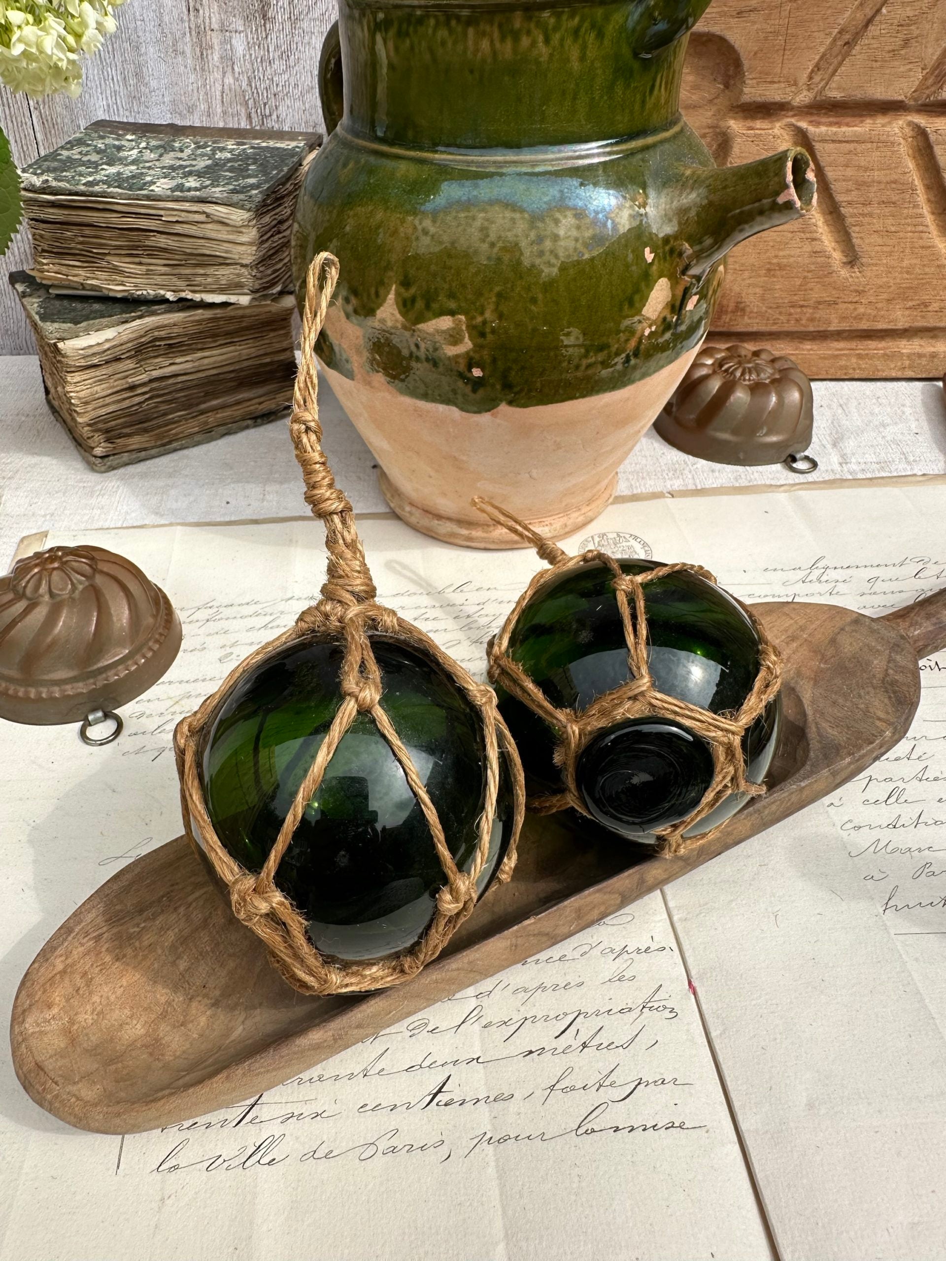 Two antique blown-glass fishing float balls with rope net