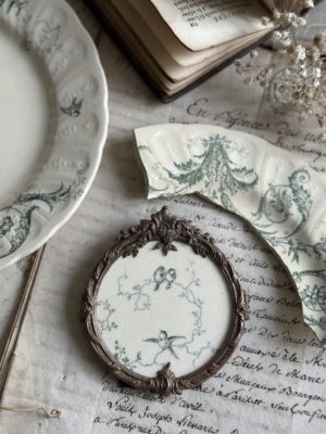 Cadre ancien rond bronze et motif terre de fer Gien Rinceaux